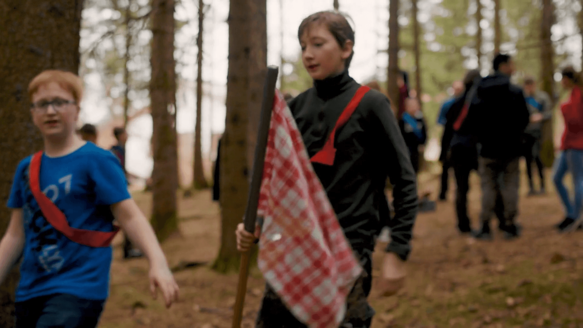 Schüler laufen beim Geländespiel mit einer Fahne durch den Wald