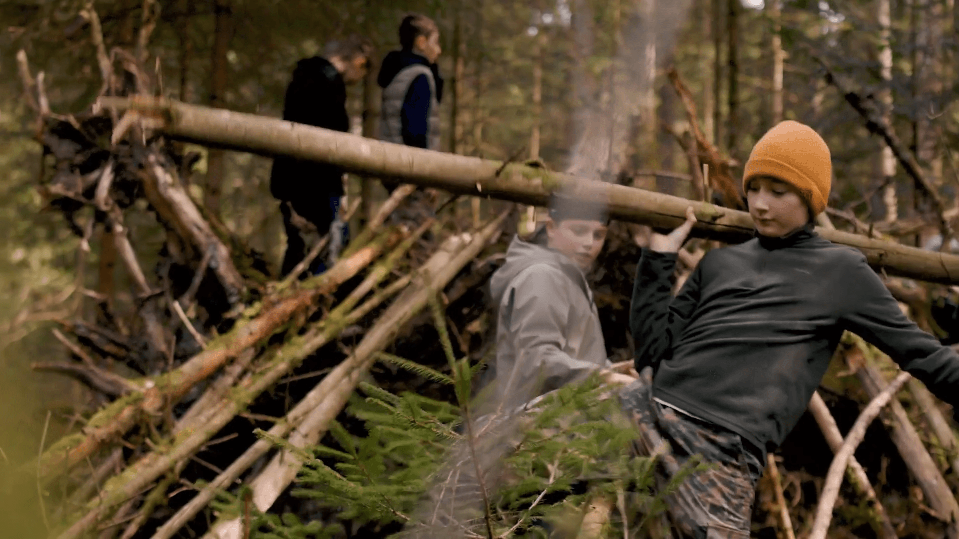 Jugendliche bauen im Wald gemeinsam einen Unterschlupf aus Ästen